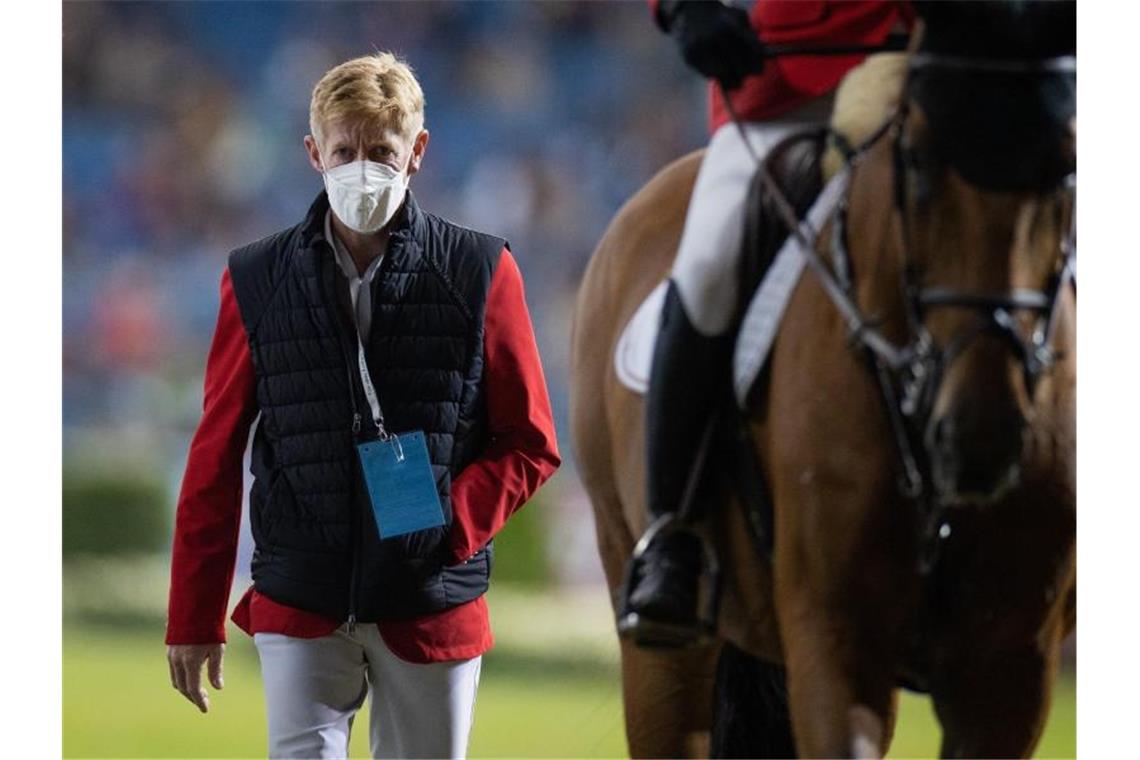 Der verletzte Reiter Marcus Ehning geht neben Daniel Deußer nach dessen Ritt aus dem Stadion. Foto: Rolf Vennenbernd/dpa