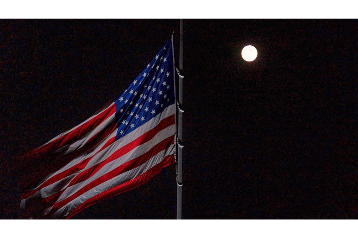 Der Vollmond geht hinter der auf Halbmast stehenden amerikanischen Flagge auf dem Südrasen des Weißen Hauses auf.