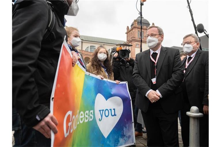 Der Vorsitzende der Deutschen Bischofskonferenz, Georg Bätzing, spricht vor der Synodalversammlung in Frankfurt mit Demonstranten, die eine vielfältigere Kirche fordern. Foto: Sebastian Gollnow/dpa