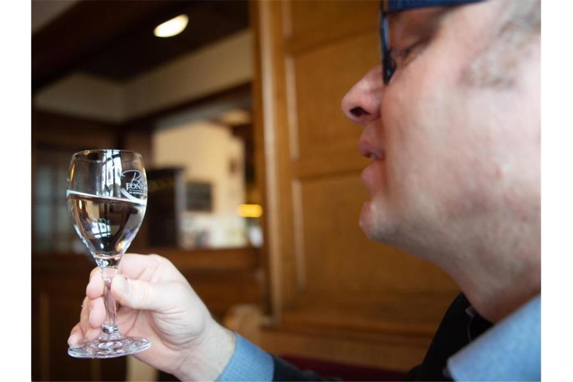 Der Wassersommelier Martin Metzinger schaut in ein Glas mit Mineralwasser. Foto: Tom Weller/dpa/Archivbild