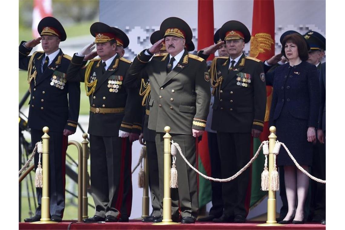 Der weißrussische Präsident Alexander Lukaschenko (M) salutiert, während er die Militärparade in Minsk verfolgt. Foto: Sergei Gapon/Pool AFP/AP/dpa