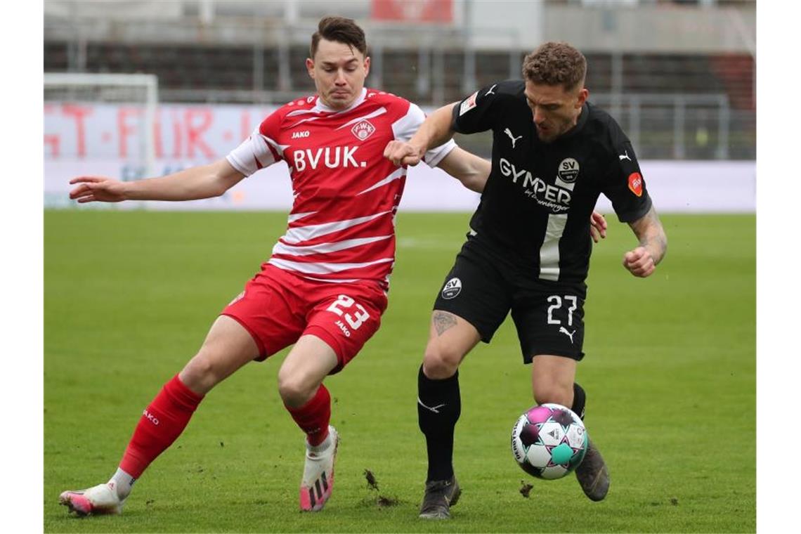 Der Würzburger Florian Flecker (l) kämpft mit Robin Scheu von Sandhausen um den Ball. Foto: Daniel Karmann/dpa