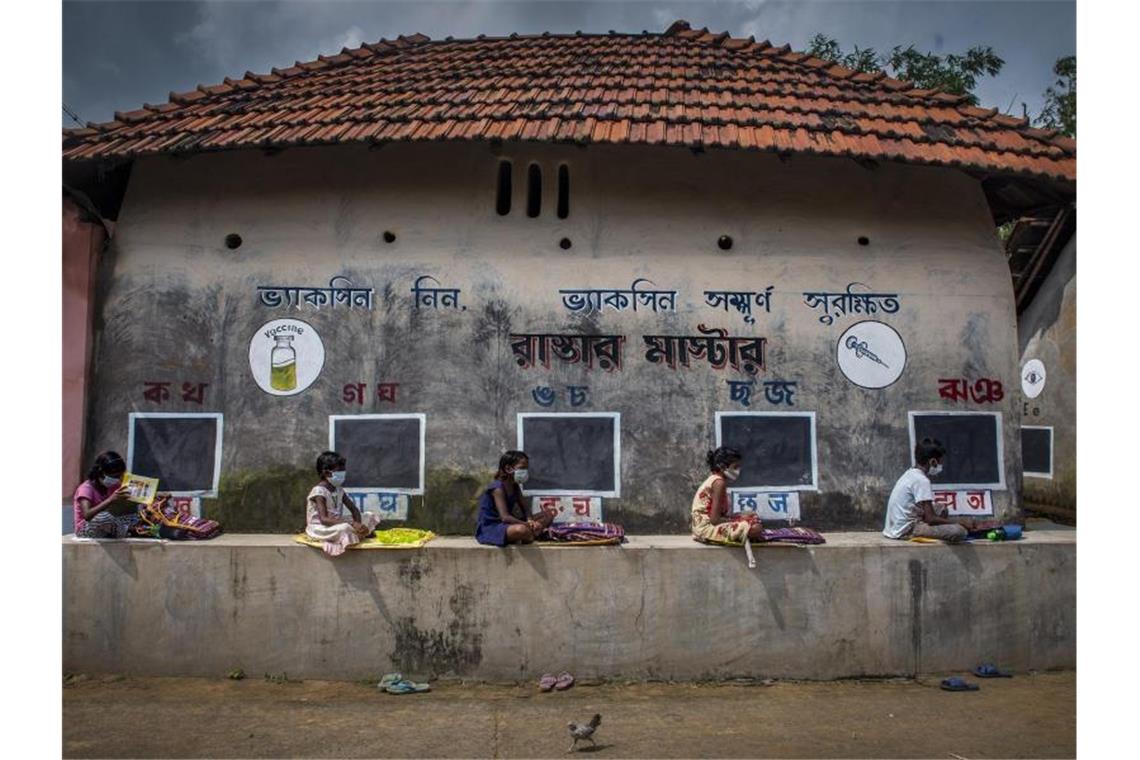 Der zweite Preis des Unicef-Wettbewerbs geht an ein Foto von Fotograf Sourav Das. Das Bild zeigt Schüler in Indien, die während der Corona-Pandemie auf einer Mauer in Abstand und mit Mund-Nasen-Schutz beim Unterricht im Freien sitzen. Foto: Sourav Das, Indien/UNICEF/dpa