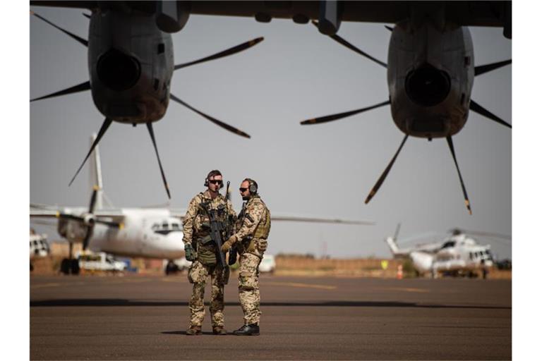 Deutsche Soldaten stehen am Flughafen in Gao und sichern ein Transportflugzeug. Foto: Arne Immanuel Bänsch/dpa