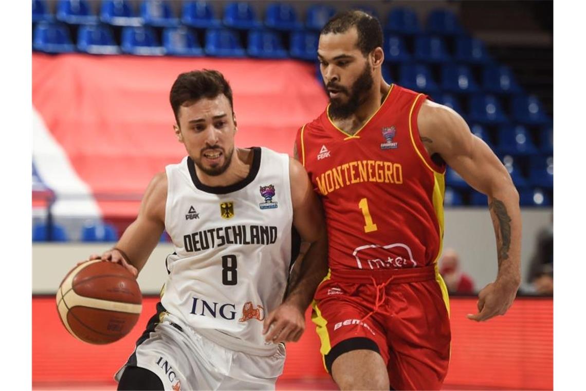 Härtetest für deutsche Basketballer gegen Frankreich Deutschlands Ismet Akpinar (l) im Duell mit Justin Cobbs aus Montenegro. Foto: Gaizka Iroz/AFP/dpa