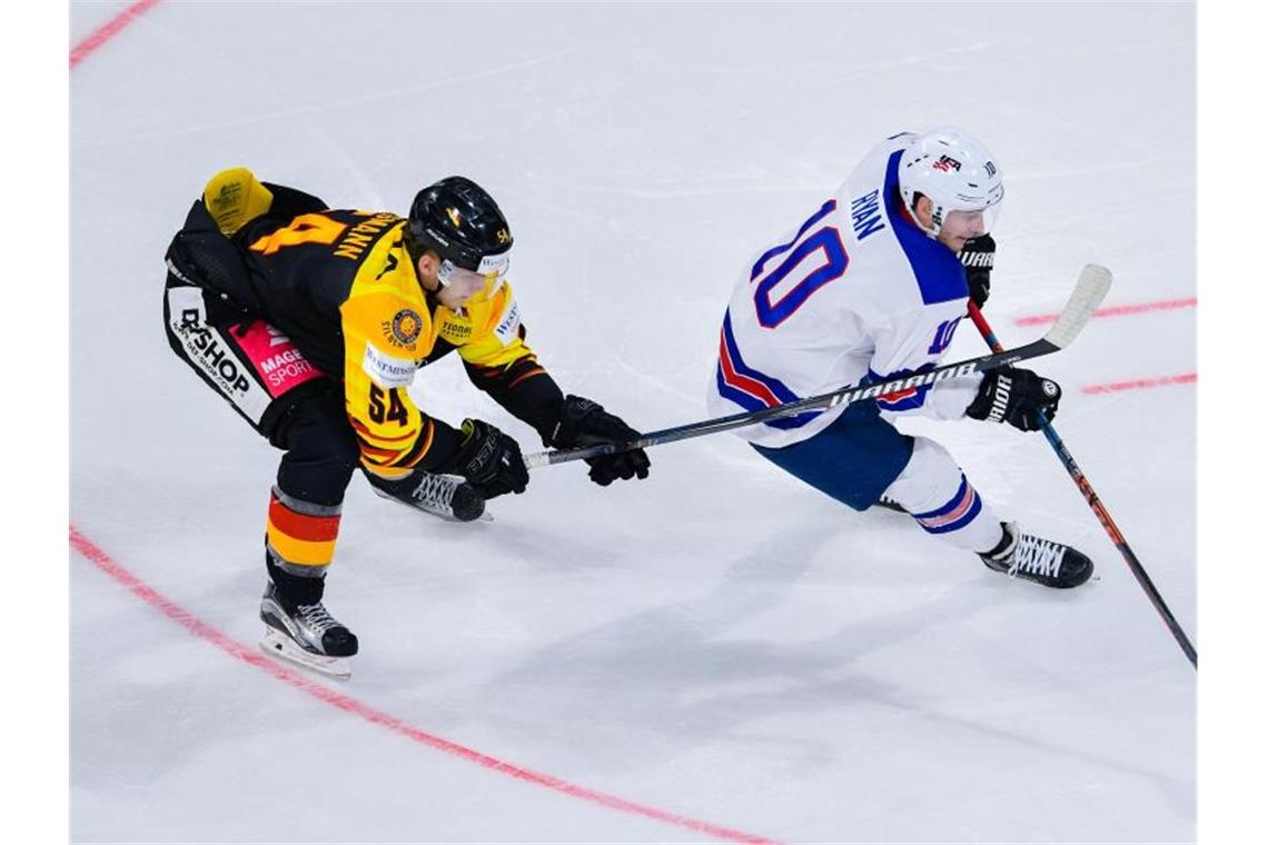 Deutschlands Lean Bergmann (l) und Derek Ryan aus den USA kämpfen um den Puck. Foto: Uwe Anspach/Archiv