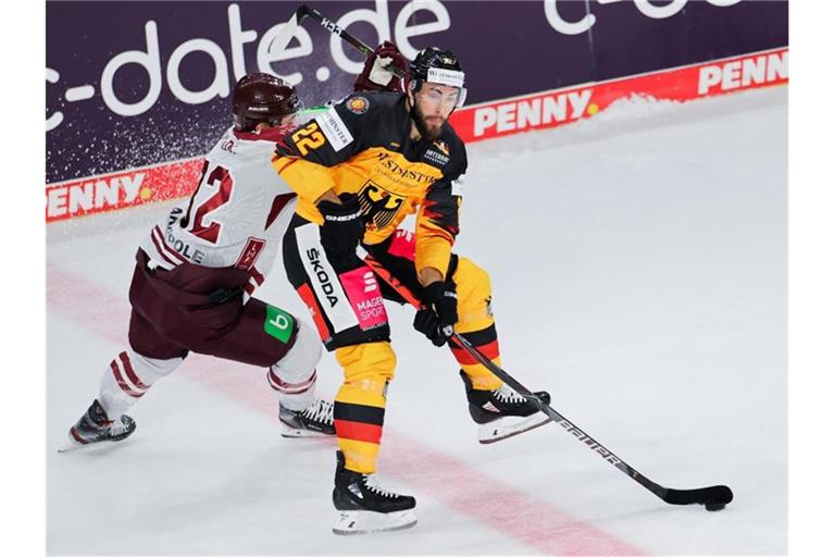 Deutschlands Matthias Plachta (r) schirmt den Puck geschickt vor Lettlands Arturs Kulda ab. Foto: Rolf Vennenbernd/dpa