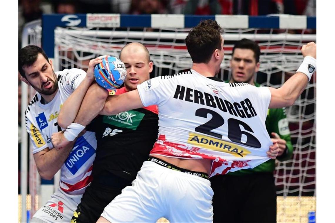 Dank Bitter: DHB-Team erreicht Spiel um Platz fünf Deutschlands Paul Drux (M) beim Zweikampf mit von Janko Bozovic (l). Foto: Robert Michael/dpa