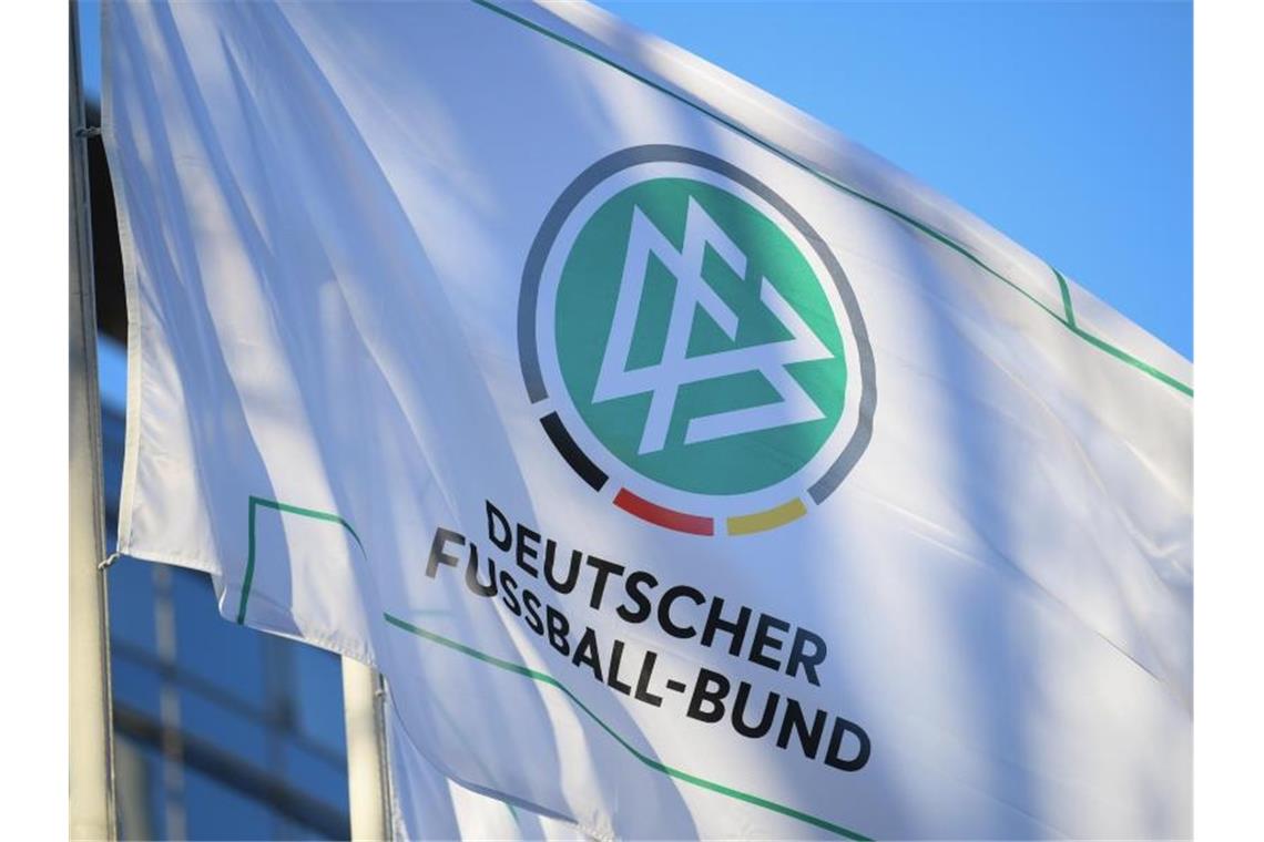 DFB-Fahnen wehen im Wind. Auf der vordersten ist das Logo des DFB zu sehen. Foto: Arne Dedert/Archiv