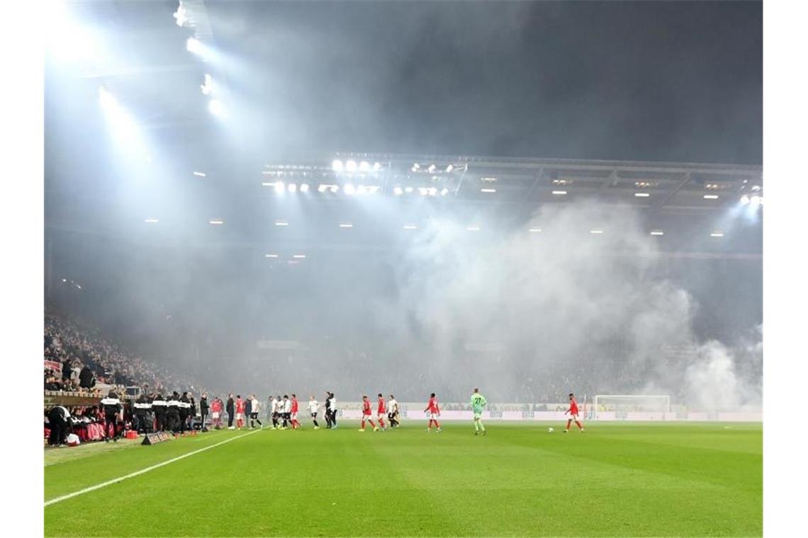 Dichte Rauchschwaden durchziehen das Stadion, nachdem Feuerwerkskörper aus dem Frankfurter Fanblock auf dem Rasen gelandet sind. Foto: Torsten Silz/dpa