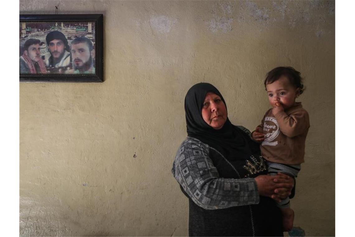 Syrien-Konferenz: Deutschland will Milliardenbetrag zusagen Die 63-jährige Syrerin Samiha Seri hält in Idlib eines ihrer 16 verwaisten Enkelkinder auf dem Arm. Hinter ihr an der Wand ein Bild mit Fotos von dreien ihrer Söhne. Foto: Anas Alkharboutli/dpa
