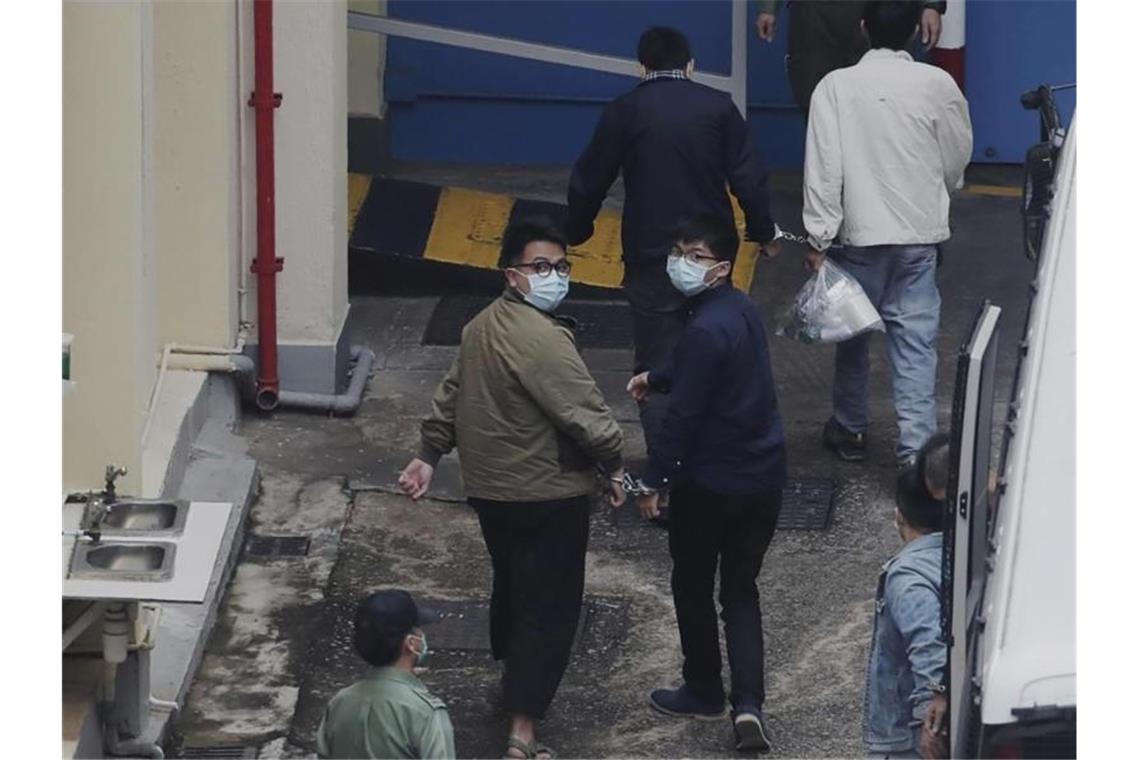 Die Aktivisten Ivan Lam (l.) und Joshua Wong wurden auf einem Gefängnishof in Hongkong von Justizvollzugsbeamten aneinandergekettet. Der prominente Hongkonger Pro-Demokratie-Aktivist Wong und zwei weitere Aktivisten, Lam und Chow, wurden in Gewahrsam genommen. Foto: Uncredited/Apple Daily/dpa