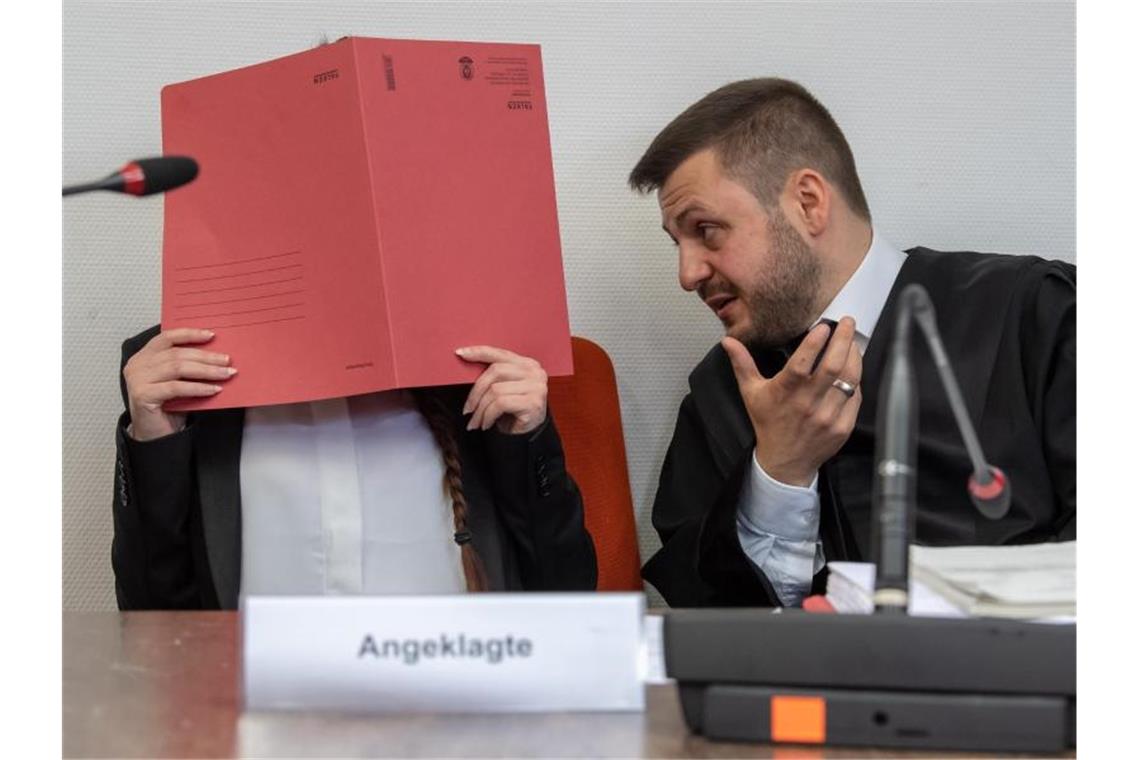 Die Angeklagte Jennifer W. im Gerichtssaal mit einem roten Aktendeckel vor ihrem Gesicht. Foto: Peter Kneffel/dpa