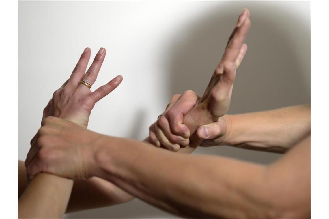 Die Arme eines Mannes (r) halten mit Gewalt die Arme einer Frau fest (gestellte Szene). Foto: Maurizio Gambarini/dpa/Symbolbild/Illustration