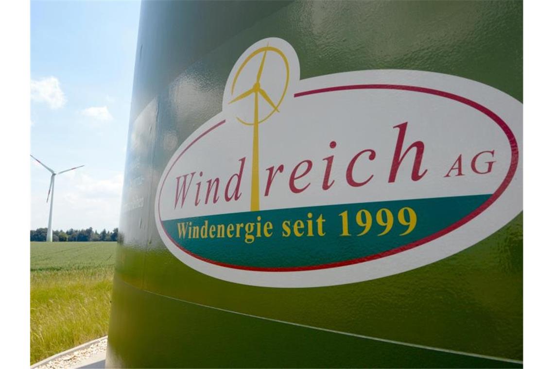 Die Aufschrift "Windreich AG. Windenergie seit 1999" steht auf einem Schild. Sschräg links im Hintergrund steht ein Windkraftwerk. Foto: Daniel Maurer/Archiv