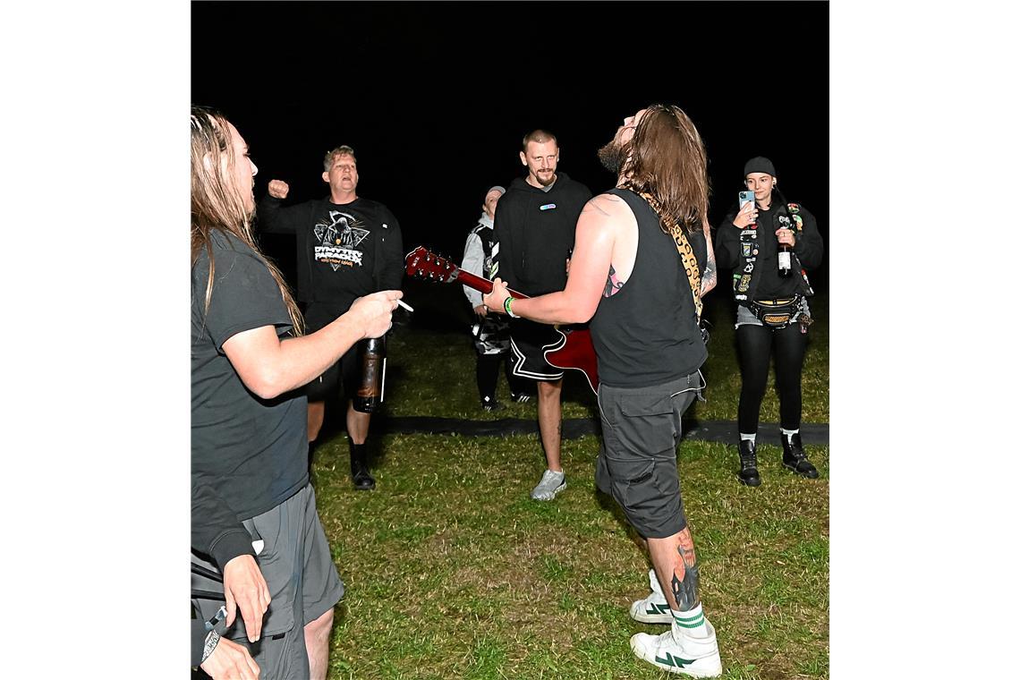 Die Band und Fans rocken gemeinsam vor der Bühne.