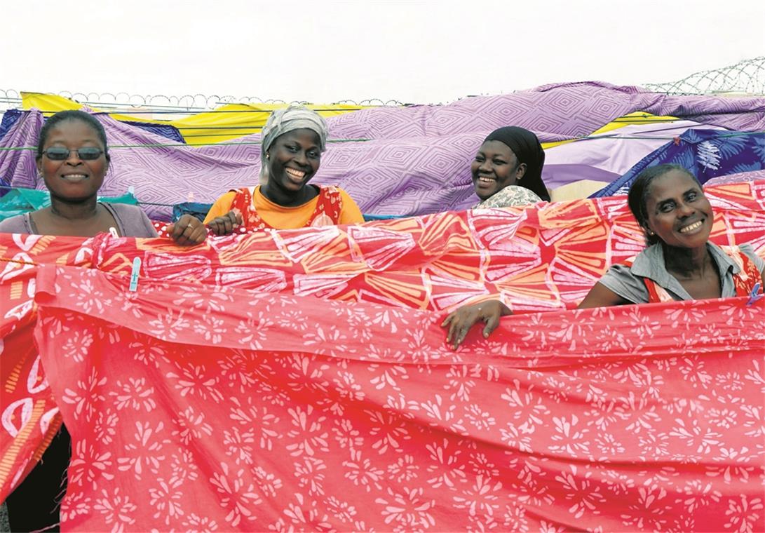 Die gelebte Vision der Global Mamas Die Batikerinnen in Ashaiman zeigen stolz ihre farbenprächtigen Produkte mit den Stempelmustern. Daraus werden Kleidungsstücke und Heimtextilien.