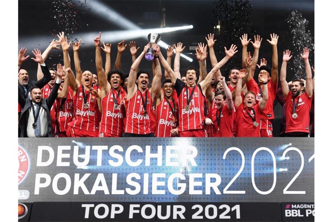 Mit Zigarre und Wein: Bayern-Basketballer feiern Pokalsieg Die Bayern jubeln nach dem Spiel mit der Trophäe. Foto: Tobias Hase/dpa