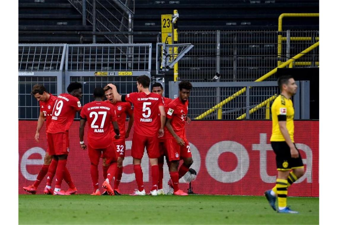 Die Bayern-Spieler feiern in Dortmund den Matchwinner Joshua Kimmich (M). Foto: Federico Gambarini/dpa-Pool/dpa