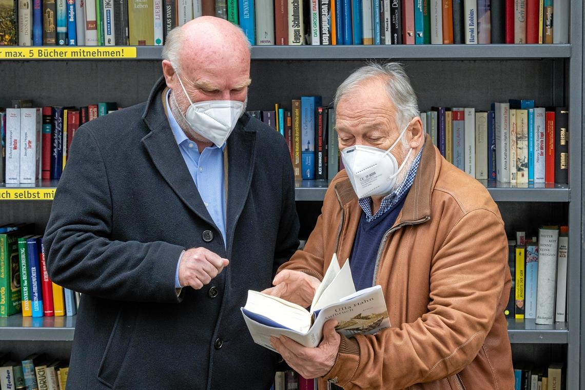 Die beiden Gründungsväter des Bücherregals Michael Balzer (von links) und Ulrich Schielke schauen in den Roman „Aufbruch“ der deutschen Schriftstellerin Ulli Hahn.