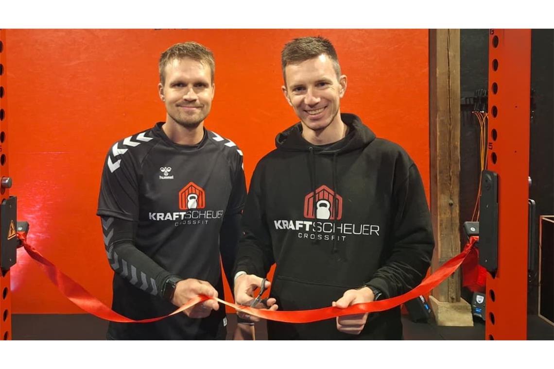 Die beiden Kraftscheuer-Gründer Nico Reinecke (li.) und Moritz Reinke (re.) zerschneiden vor dem ersten Gruppen-Workout im neuen Studio symbolisch ein rotes Band.