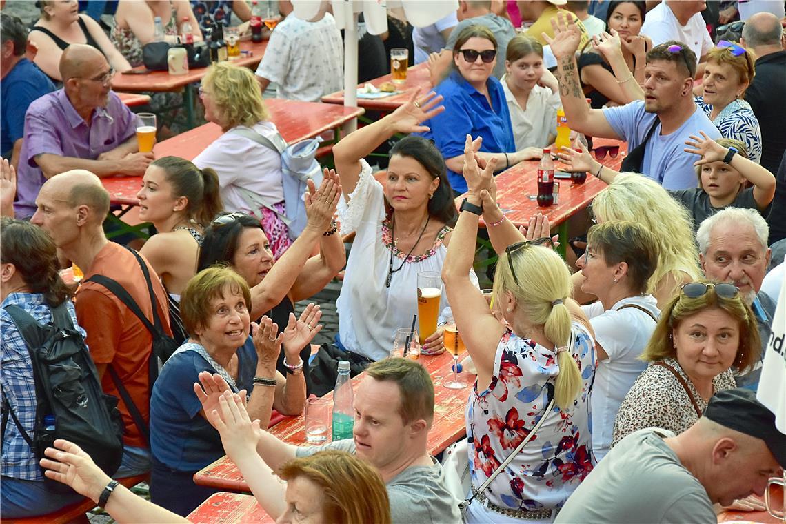 Die Besucherinnen und Besucher auf dem Marktplatz klatschen zu bekannten Hits mi...