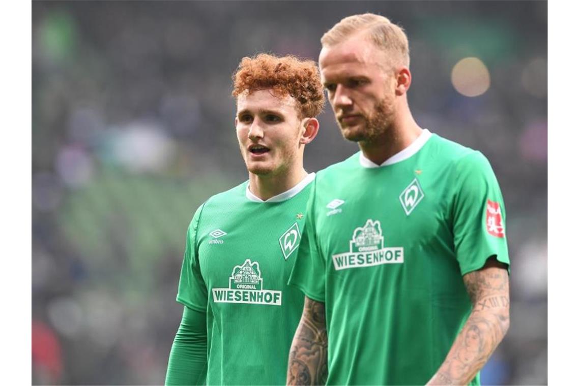 Die Bremer Kevin Vogt (r) und Josh Sargent laufen enttäuscht über den Rasen. Foto: Carmen Jaspersen/dpa