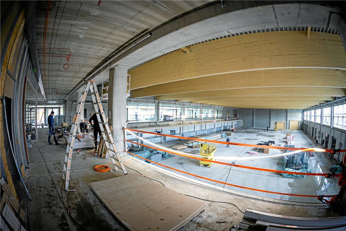 Wie aus dem Rohbau eine Sporthalle wird Die Dachträger aus Lärchenholz sind ein Blickfang in der neuen Sporthalle. Rund 50 Handwerker sind hier derzeit mit dem Innenausbau beschäftigt. Solange der Sportboden noch nicht eingebaut ist, kommen dabei auch Hebebühnen zum Einsatz. Fotos: Alexander Becher