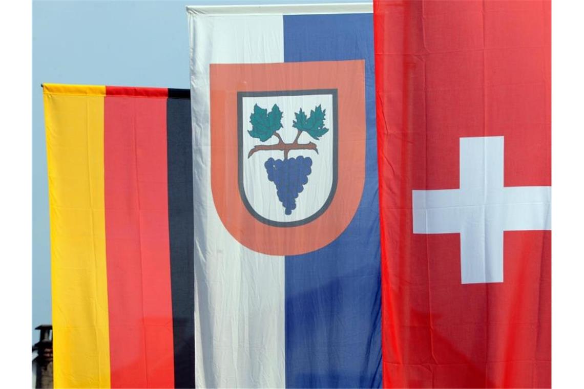 Die deutsche, die Büsinger und die Schweizer Flagge (l-r) sind in Büsingen gehisst. Foto: Patrick Seeger/dpa/Symbolbild