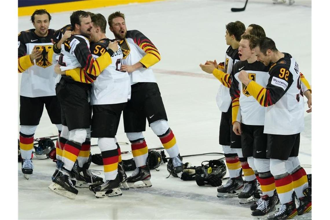 Die deutschen Nationalspieler feiern ihren Erfolg auf dem Eis. Foto: Roman Koksarov/dpa