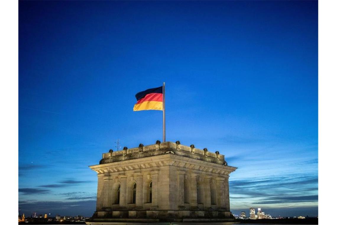 Corona-Krise trübt die Stimmung der Deutschen Die Deutschlandfahne weht vor dem Abendhimmel auf dem Reichstagsgebäude im Wind. Foto: Kay Nietfeld/dpa