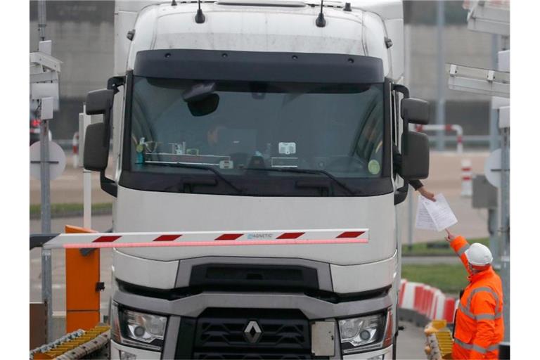 Die Dokumente eines Lastwagenfahrers werden kontrolliert, als der Lkw den Check-in für den Zug durch den Eurotunnel passiert. Foto: Frank Augstein/AP/dpa