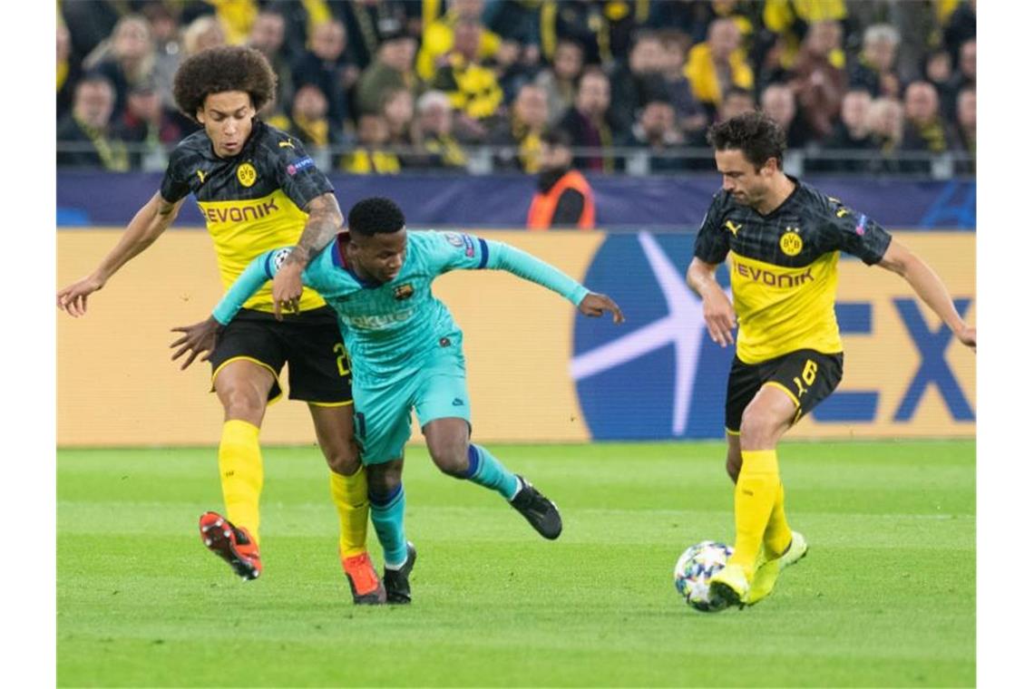 Die Dortmunder Axel Witsel (l) und Thomas Delaney (r) nehmen Ansu Fati vom FC Barcelona den Ball ab. Foto: Bernd Thissen