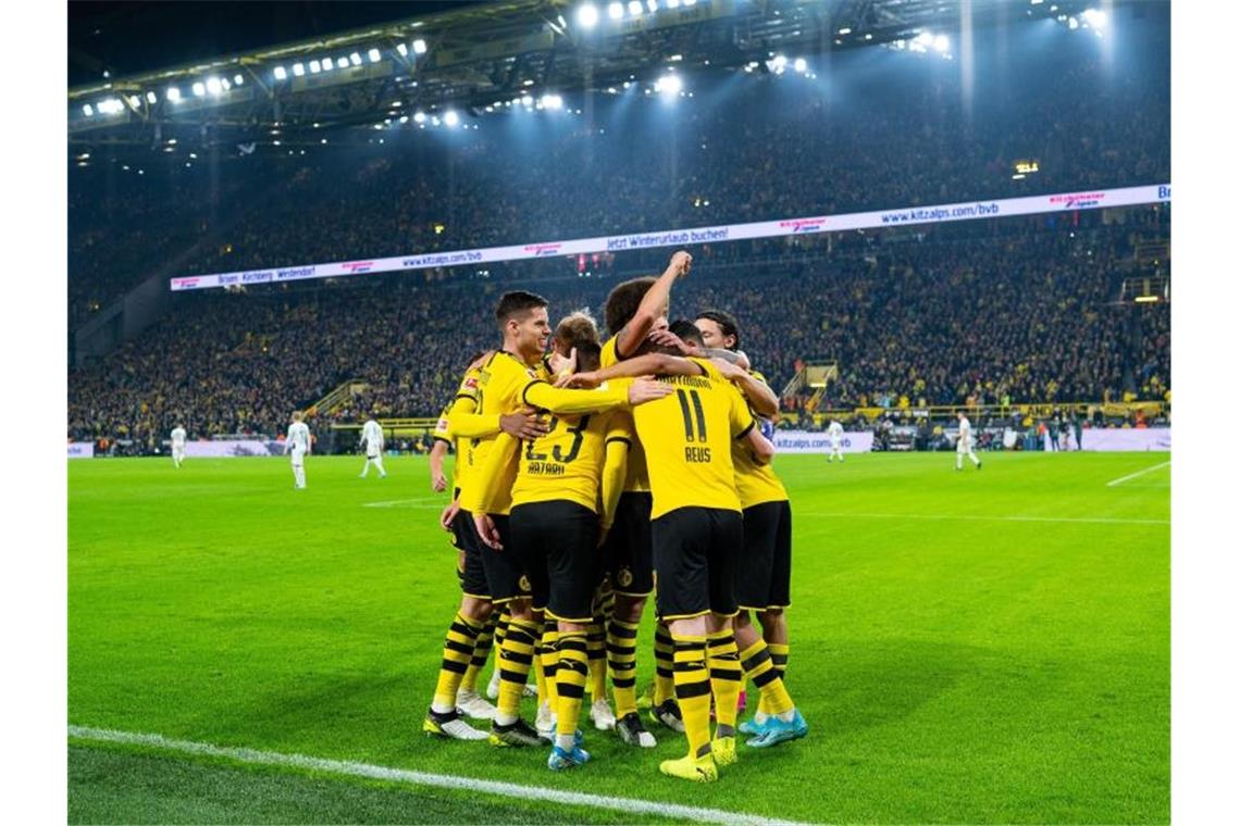 Die Dortmunder Spieler um Dortmunds Torschütze Marco Reus bejubeln das Siegtor. Foto: Guido Kirchner/dpa