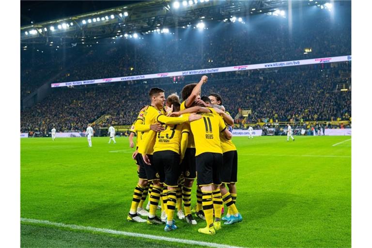 Die Dortmunder Spieler um Dortmunds Torschütze Marco Reus bejubeln das Siegtor. Foto: Guido Kirchner/dpa