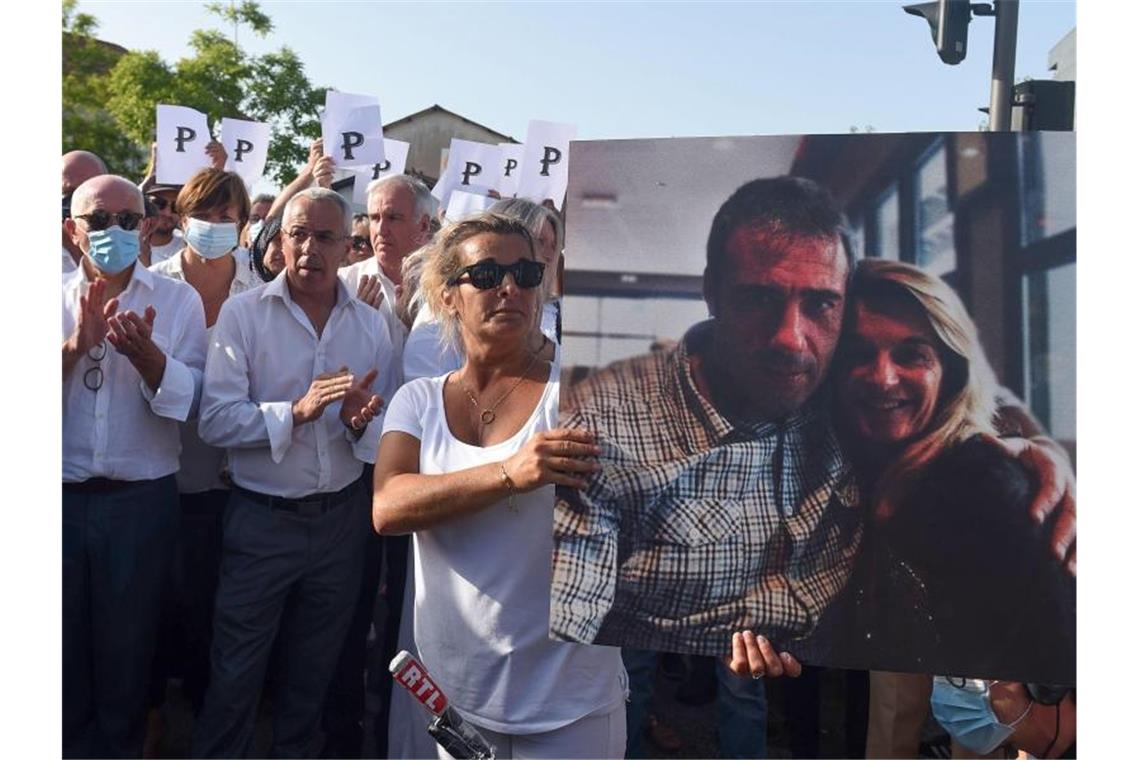 Die Ehefrau des verstorbenen Busfahrers hält während eines Protestmarsches in Bayonne ein Foto von sich und ihrem Mann. Foto: Gaizka Iroz/AFP/dpa