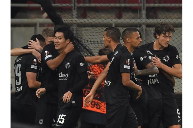 Die Eintracht-Spieler feiern den Sieg in Piräus. Foto: Angelos Tzortzinis/dpa