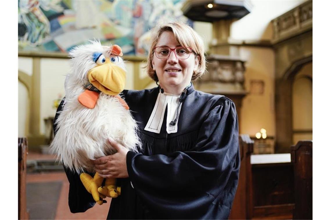 Die evangelische Pfarrerin und Bauchrednerin Maibritt Gustrau sowie ihre Figur, der Hahn Otto. Foto: Uwe Anspach/dpa/Archivbild