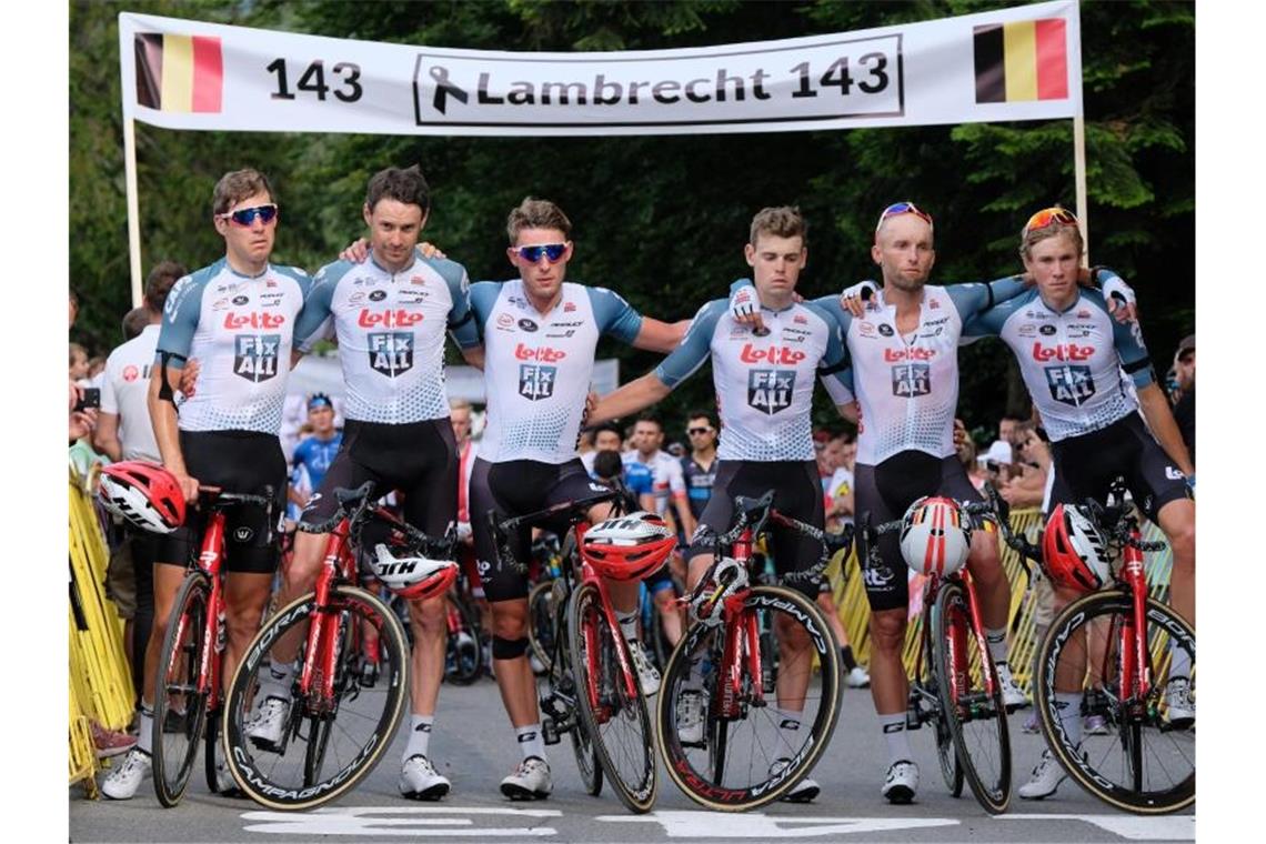 Die Fahrer des Teams Lotto Soudal stehen für eine Schweigeminute zum Tod von Bjorg Lambrecht mit Trauerflor vor einem Banner. Foto: Hanna Bardo/PAP