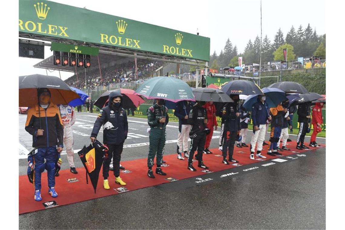 Die Fahrer stehen vor dem Start zusammen im Regen. Foto: John Thys/Pool AFP/AP/dpa