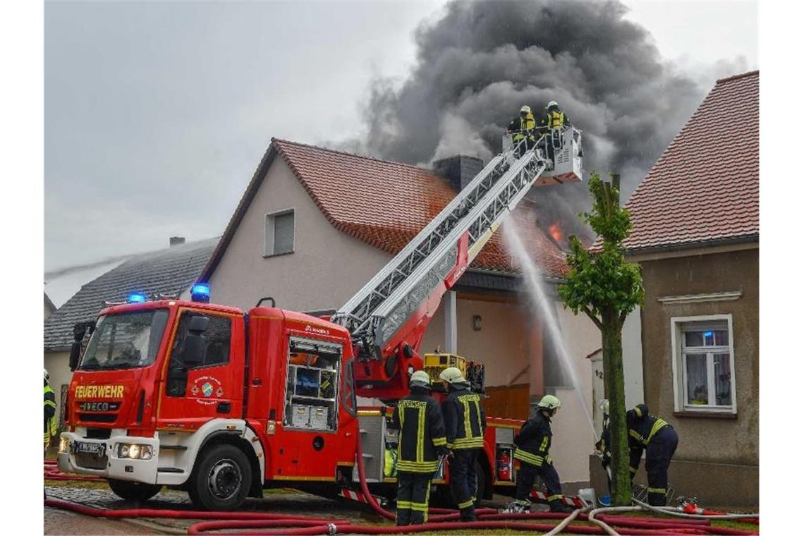 Die Feuerwehr löscht in Leitzkau in Sachsen-Anhalt einen Brand an einem Wohnhaus. Ein Blitz hatte den Dachstuhl in Brand gesetzt. Foto: Tom Wunderlich