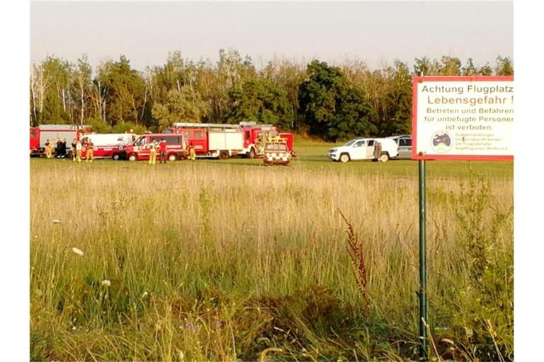 Die Feuerwehr steht am Flugplatz Renneritz an der weiträumig abgesperrten Unfallstelle. Foto: Heiko Rebsch/dpa-Zentralbild/dpa