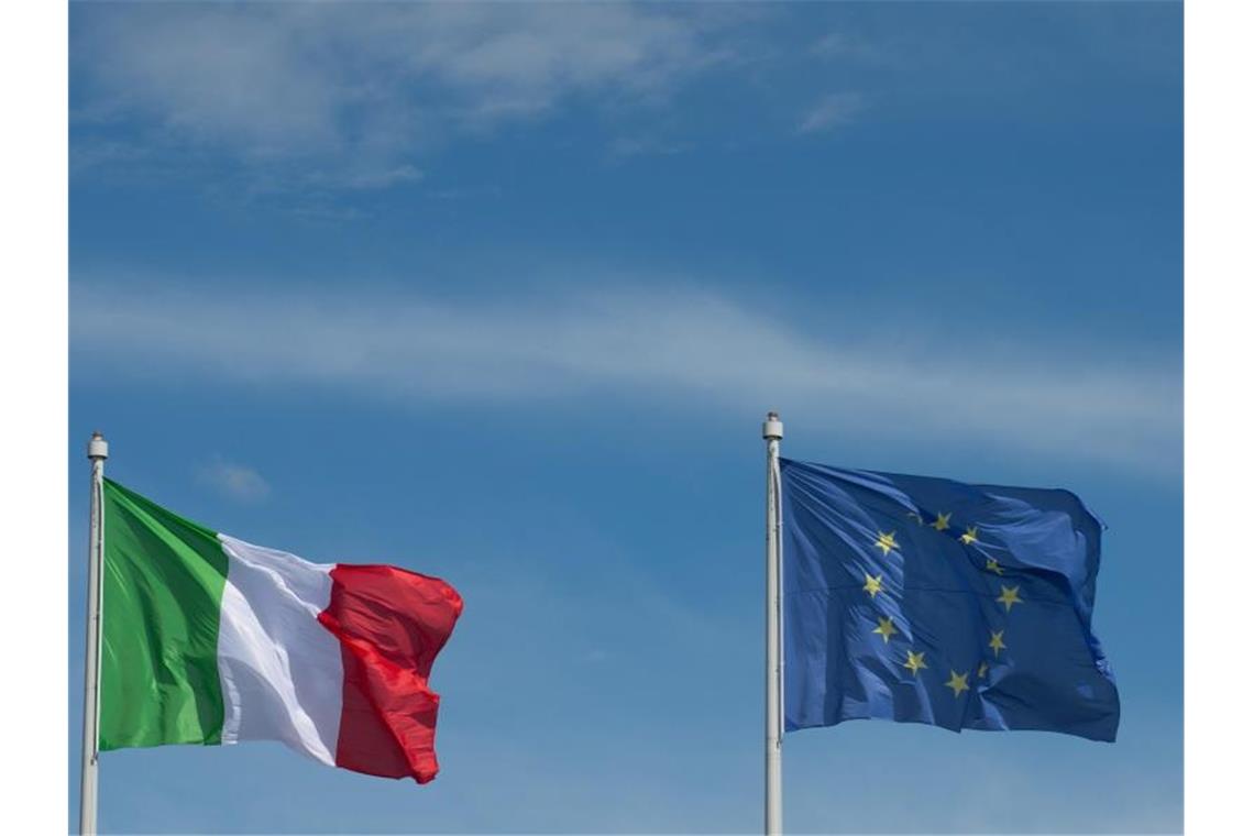 Die Flaggen der EU und Italiens: Die EU-Kommission empfiehlt ein Strafverfahren gegen das Land. Foto: Marijan Murat