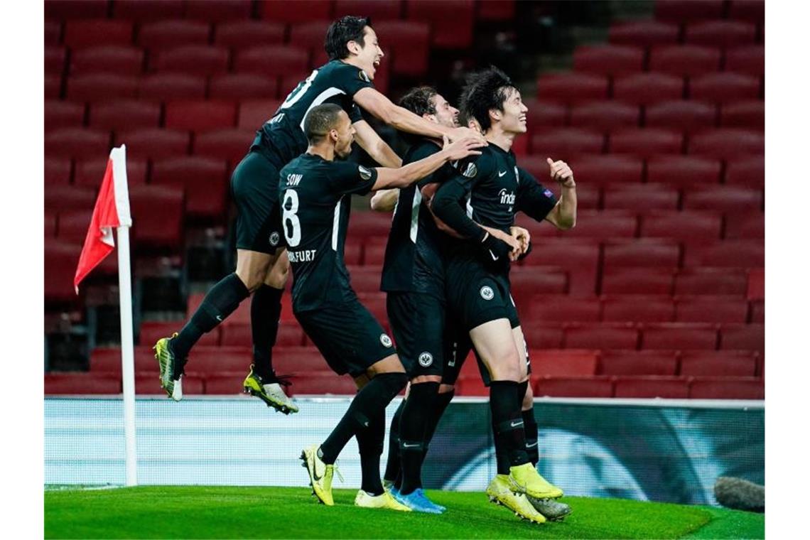 Die Frankfurter feiern den Treffer zum 2:1-Sieg beim FC Arsenal durch Daichi Kamada (r). Foto: Uwe Anspach/dpa