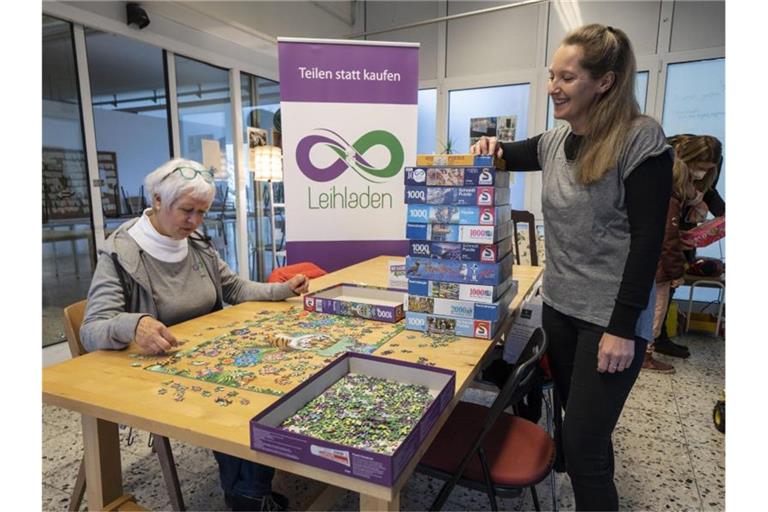 Die freiwilligen Mitarbeiterinnen Anne Deneke (l) und Dana Lorentz-Sengöz stehen vor einem Stapel Puzzles, die man ausleihen kann. Foto: Frank Rumpenhorst/dpa
