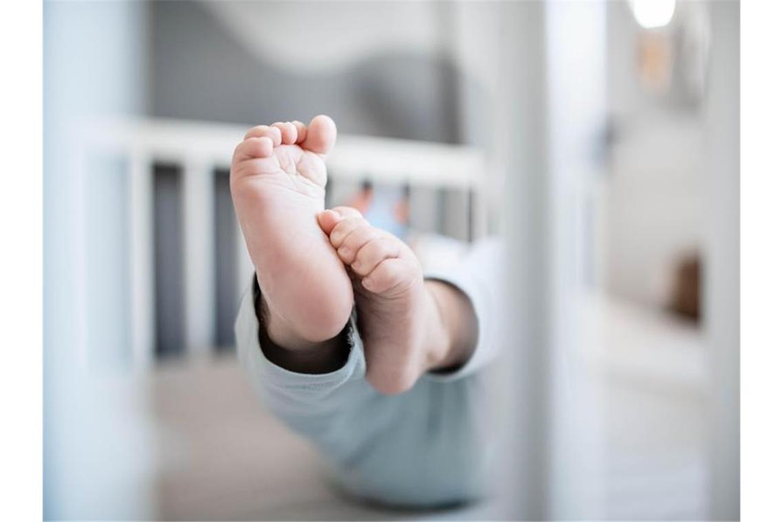 Die Füße eines Babys sind in einem Kinderbett zu sehen. Foto: Fabian Strauch/dpa/Illustration