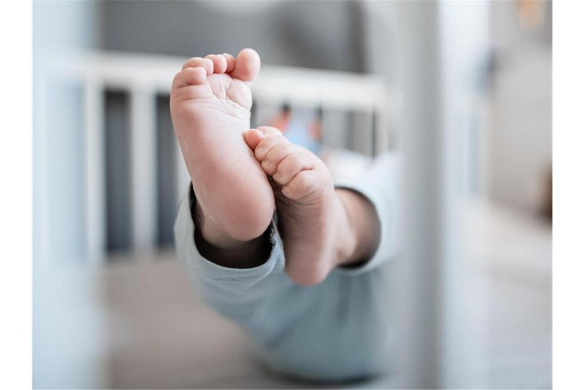 Die Füße eines Babys sind in einem Kinderbett zu sehen. Foto: Fabian Strauch/dpa
