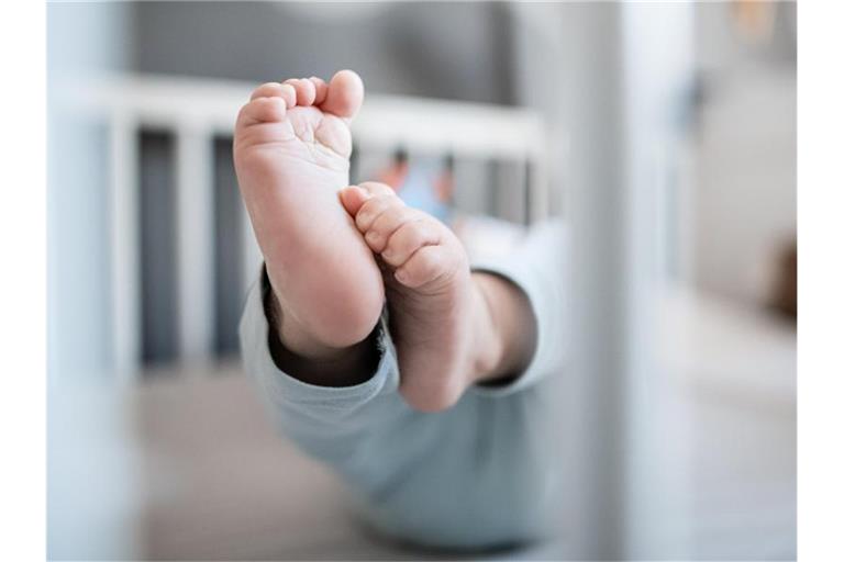 Die Füße eines Babys sind in einem Kinderbett zu sehen. Foto: Fabian Strauch/dpa/Symbolbild