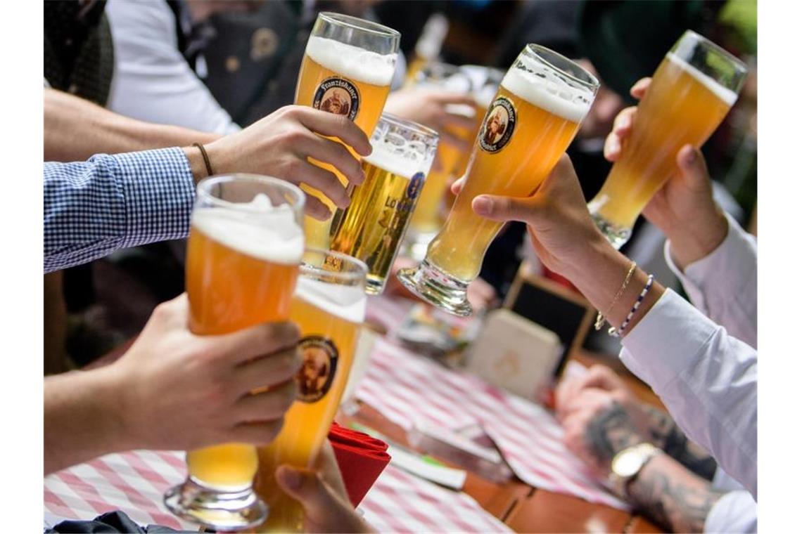 Die Gäste sind zahlreich vorhanden, aber Mitarbeiter in der Gastronomie sind schwer zu finden. Eine Männergruppe stößt im Biergarten eines Wirtshauses an der Isar mit Weißbiergläsern an. Foto: Matthias Balk