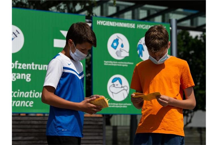 Die Geschwister-Impflinge Hugo (12 Jahre) und Urs (13 Jahre) blättern vor ihrer Impfung in ihren Impfbüchern. Foto: Swen Pförtner/dpa